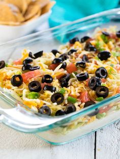 a casserole dish with black olives, tomatoes, and rice in it