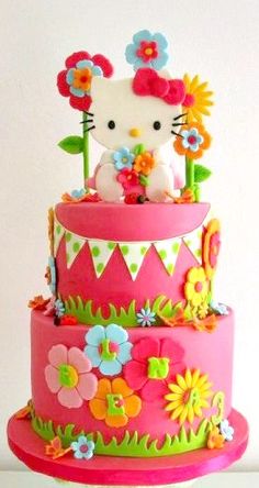 a hello kitty birthday cake with flowers and bunting on the top is decorated in bright colors