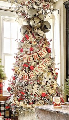 a christmas tree decorated with red and white ribbon, silver bells, ornaments and letters