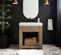 a white sink sitting under a mirror next to a potted plant in a bathroom