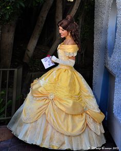 a woman in a yellow dress is holding a piece of paper