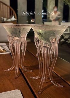 two clear glass vases sitting on top of a wooden table next to each other