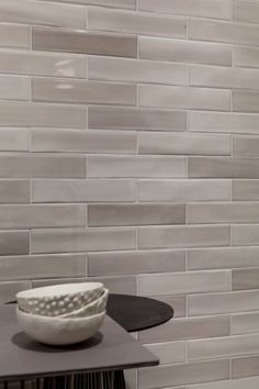 a white bowl sitting on top of a table next to a black and white tile wall