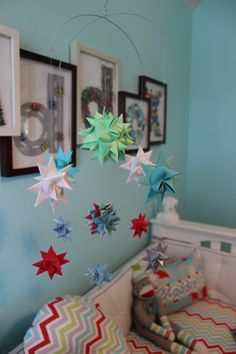 a baby crib with several stars hanging from it's ceiling and pictures on the wall