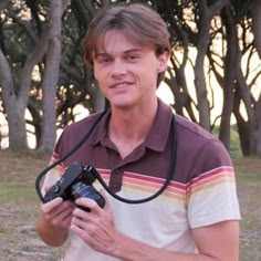 a man holding a camera in front of trees