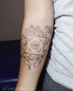 a woman's arm with a tattoo on it that has flowers and a square in the middle