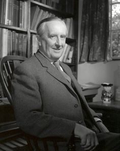 black and white photograph of a man in a suit sitting in front of a bookshelf