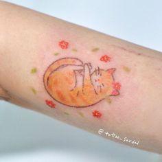 a small tattoo on the arm of a woman with a cat sleeping on it's back