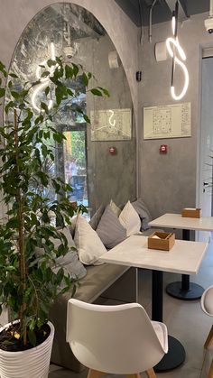 a room with tables, chairs and a potted plant