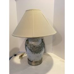 a lamp that is sitting on top of a white table with a shade over it