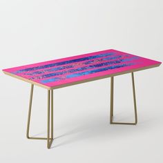 a pink and blue table with gold legs on a white background that has an abstract design in the middle