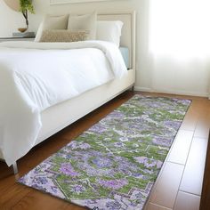 a large bed sitting next to a window on top of a hard wood floor