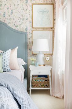 a bedroom with floral wallpaper and blue headboard on the nightstand next to the bed