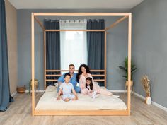 a family is sitting on a bed in their bedroom with blue curtains and drapes