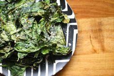 a white plate topped with greens on top of a wooden table