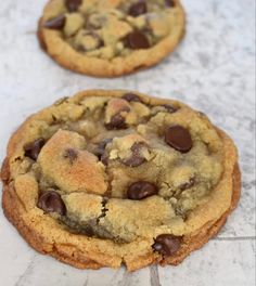 two chocolate chip cookies sitting on top of a counter