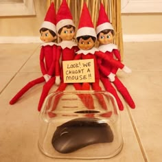 three elfs sitting on top of a mouse pad with a sign that says, look we caught a mouse