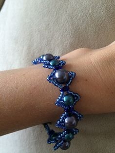 a close up of a person's arm wearing a bracelet with pearls on it