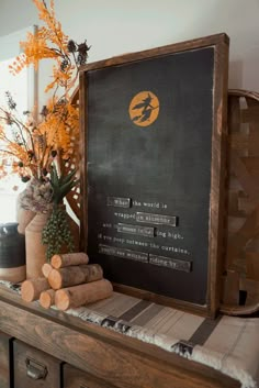 a wooden table topped with vases filled with yellow flowers and wood logs next to a chalkboard