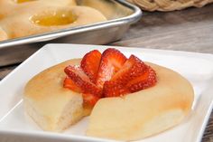 some food is on a white plate and next to two pans with pastries