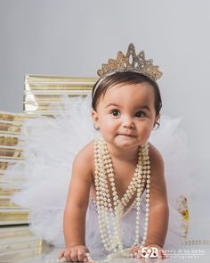 a baby girl wearing pearls and a tiara