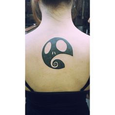 the back of a woman's neck with a yin symbol tattoo on her left shoulder