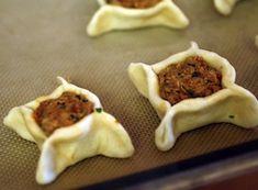 dumplings with meat in them sitting on a baking sheet