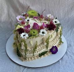 a white cake with flowers on it sitting on a plate