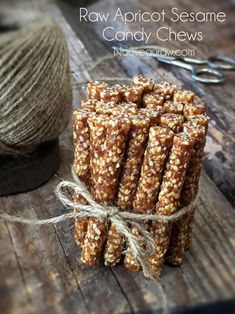 raw apricot sesame candy chews are tied up on a wooden table with twine