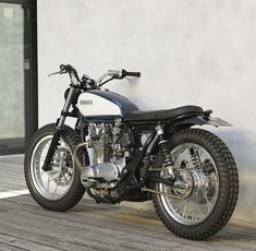 a black and white motorcycle parked on top of a wooden floor next to a building