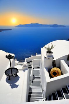 the sun is setting over an island with stairs leading up to it and some plants in pots