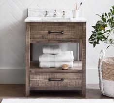 a bathroom vanity with white towels on it and a potted plant next to it