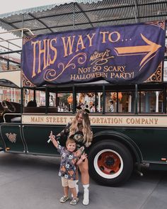 a woman standing next to a child in front of a bus with a sign on it