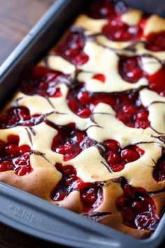 a pan filled with cherry cheesecake on top of a wooden table