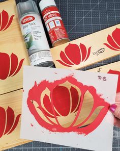 some red flowers are being painted on wood