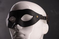 This stunning winged black mask, accentuated by rich bronze hardware, offers an alluring contrast that exudes elegance and intrigue. Ideal for those who want to balance edginess with a touch of vintage charm. Sabersmyth's leather masks are a bold blend of artistry, comfort, and durability. Each mask is expertly shaped to fit the unique contours of your face, offering both a snug fit and lasting comfort. Spacious eye openings ensure clear peripheral vision and won't interfere with your makeup, while our signature head cradle design guarantees a secure, comfortable wear. Designed to make a statement and built to last, these masks will be the envy of every event. Leather Masks, Peripheral Vision, Costume Masks, Mask Black, Leather Mask, Bronze Hardware, Costume Mask, Black Mask, Costume Accessories