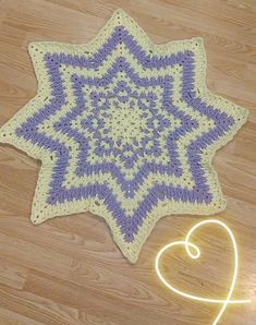 a purple and white crocheted star is on the floor next to a heart