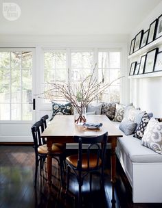 a dining room table with chairs and a bench in front of the window that is open