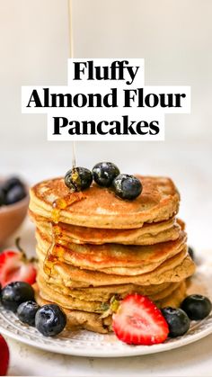 stack of pancakes with blueberries and strawberries on the side