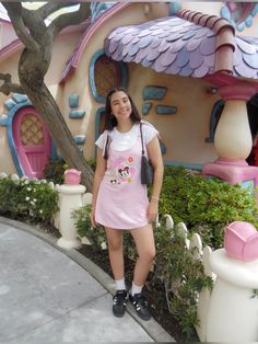 a woman standing in front of a pink and white house with mickey mouse on it