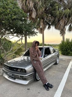 a man sitting on the hood of a car talking on a cell phone