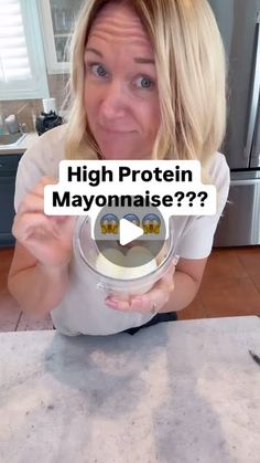 a woman is holding up a sign that says high protein mayonnaise? in front of her face