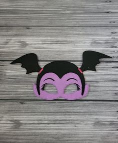 a purple mask with black wings on top of wooden planks and a gray background