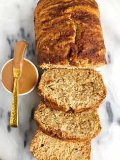 slices of banana bread next to a bowl of peanut butter and a spoon on a marble surface