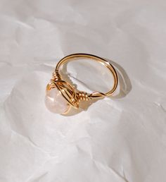 This ring is handcrafted with gold plated brass wire and comes with a grade A designer quality rose quartz crystal bead imported from Japan, featuring a unique minimalist beauty. Please note that the gold plated wire is 20 gauge (pictured) tarnish resistant gold colored copper wire. The sterling silver and 14k gold-filled options use 22 gauge wire (a slightly thinner wire wrapping option). All pieces are made with lots of love! I hope that my creations can spark some joy into your hearts <3 Gold Minimalist Crystal Ring With Moonstone, Minimalist Gold Moonstone Crystal Ring, Adjustable Gold Crystal Ring With Moonstone, Adjustable Minimalist Rose Gold Crystal Ring, Minimalist Adjustable Rose Gold Crystal Ring, Delicate Adjustable Gold Moonstone Ring, Minimalist Hand Wrapped Crystal Promise Ring, Handmade Minimalist Rose Quartz Jewelry, Minimalist Hand Wrapped Rose Gold Jewelry