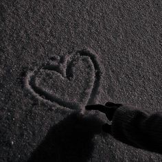 someone is drawing a heart in the snow