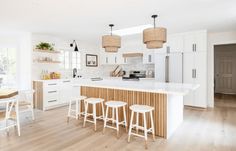 an open kitchen with white cabinets and wooden stools in front of the island counter