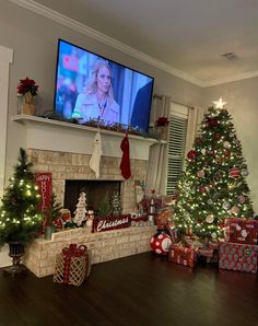 a living room decorated for christmas with presents on the fireplace and tv in the corner