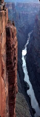 a man standing on the edge of a cliff overlooking a river and canyon below him