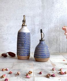 two blue and white vases sitting on top of a tile floor next to pink flowers